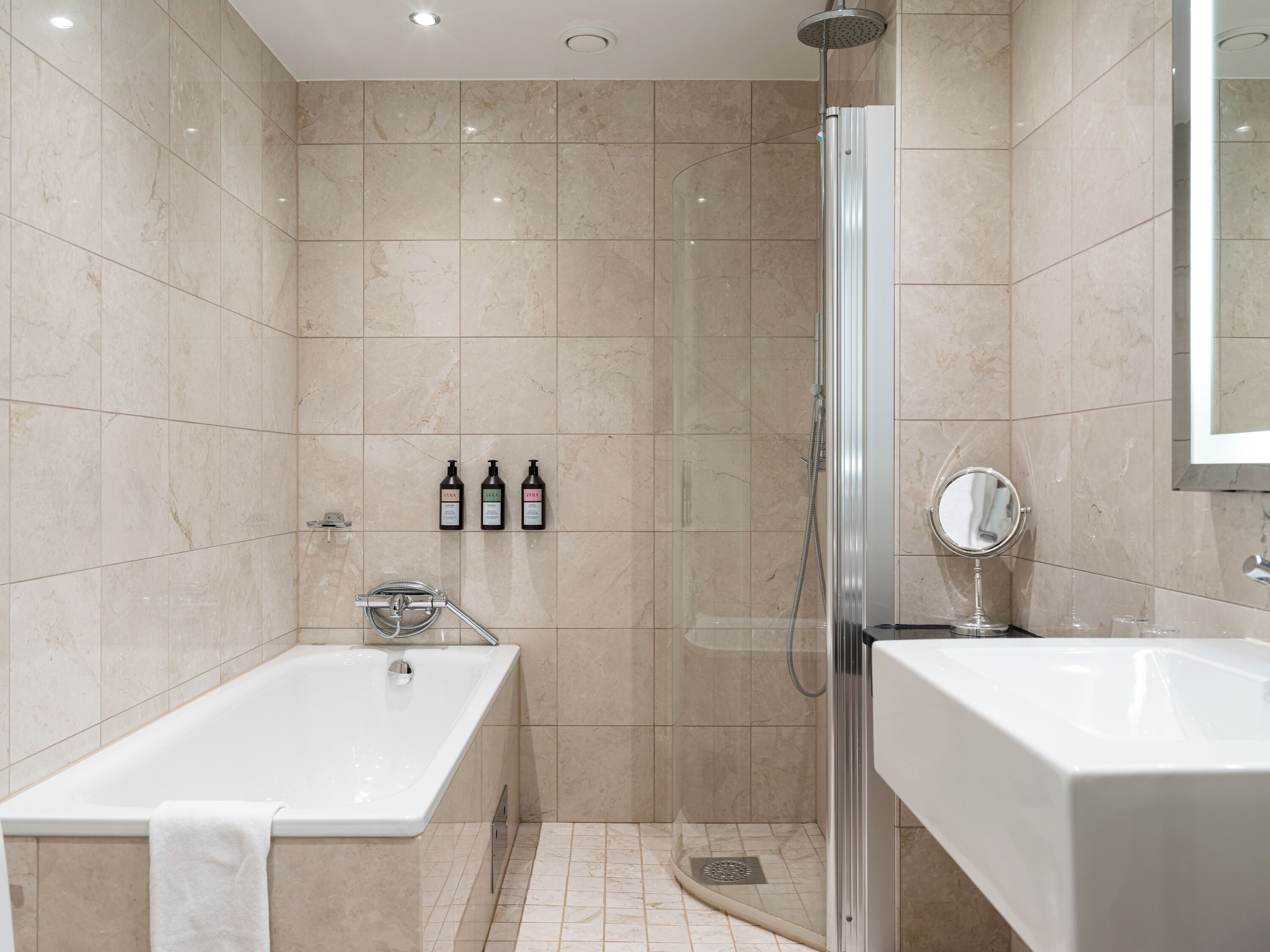 Une salle de bain moderne équipée d’une baignoire, d’une douche et d’un meuble-lavabo avec un miroir.