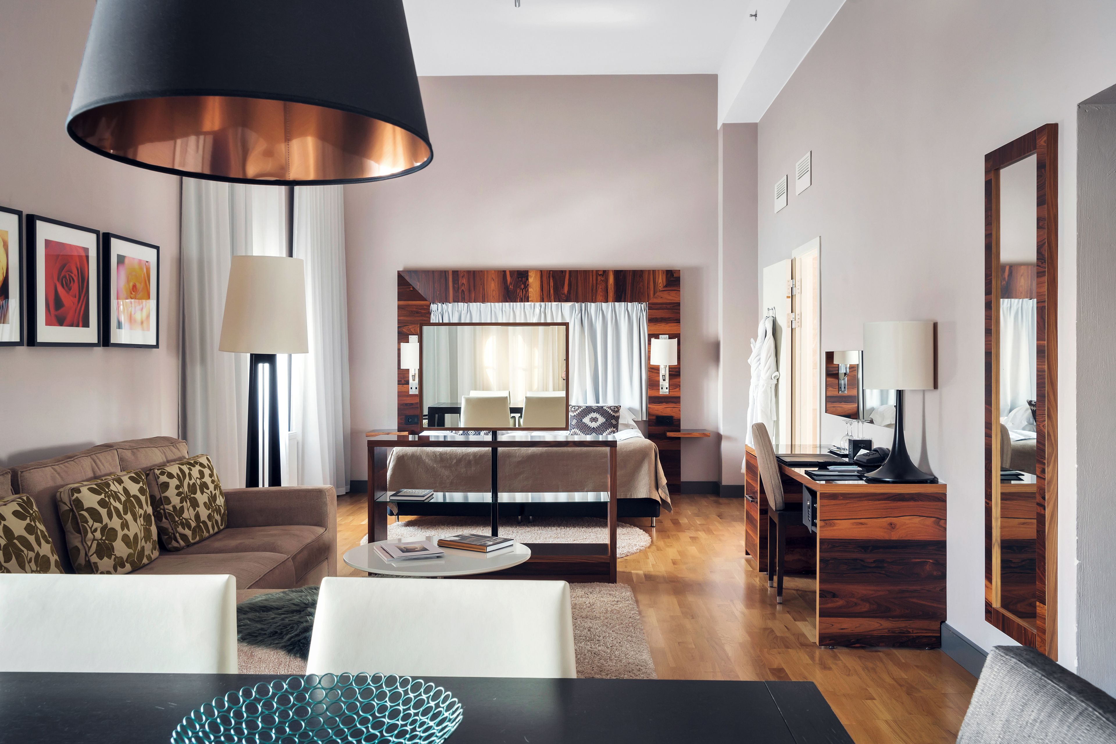Una habitación de hotel moderna con cama, escritorio, zona de comedor y sala de estar.