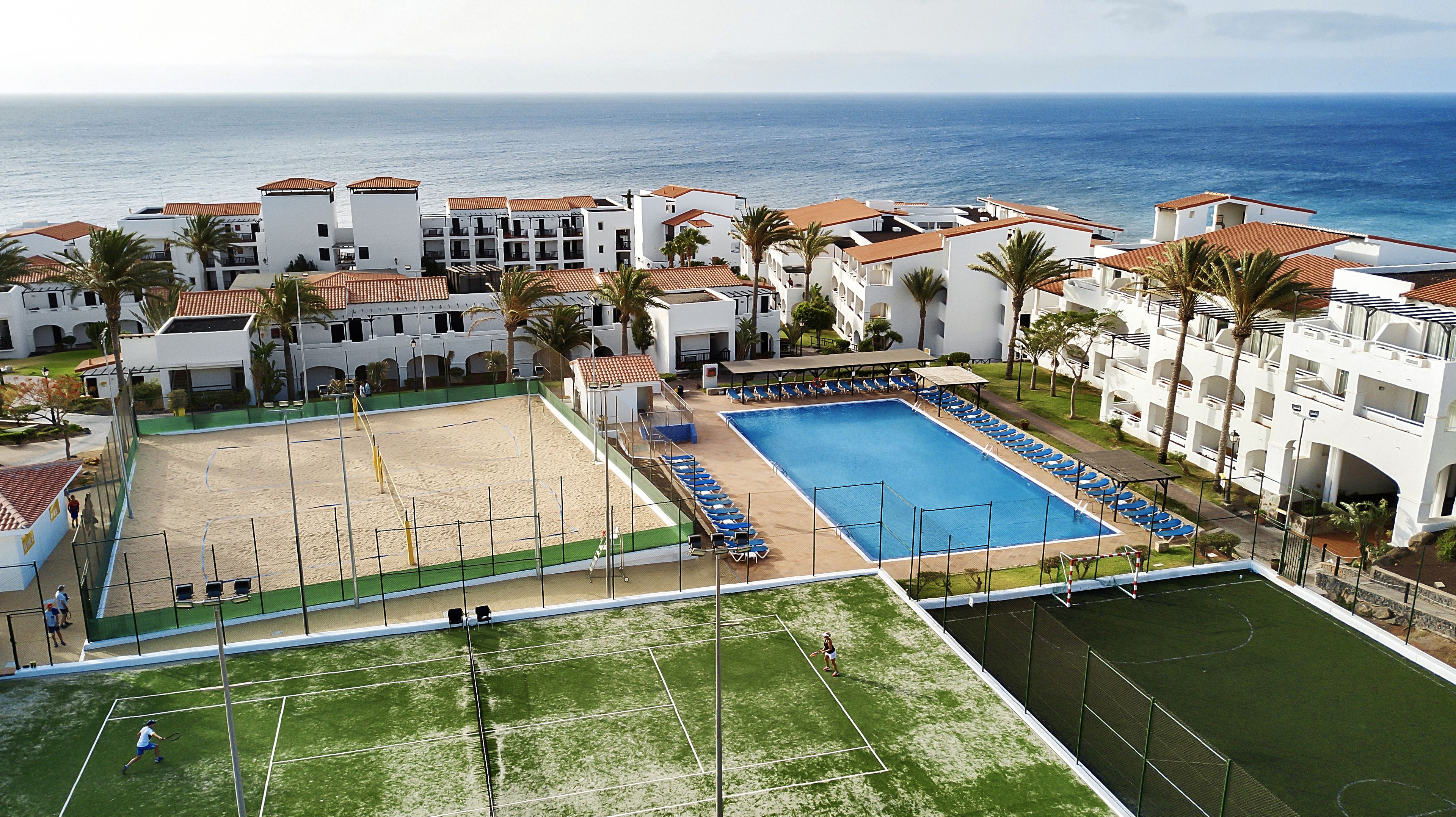 A resort with a swimming pool, tennis courts, and a beach area.