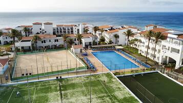 A resort with a swimming pool, tennis courts, and a beach area.