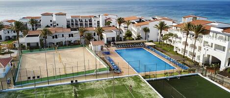 Un resort con piscina, canchas de tenis y zona de playa.