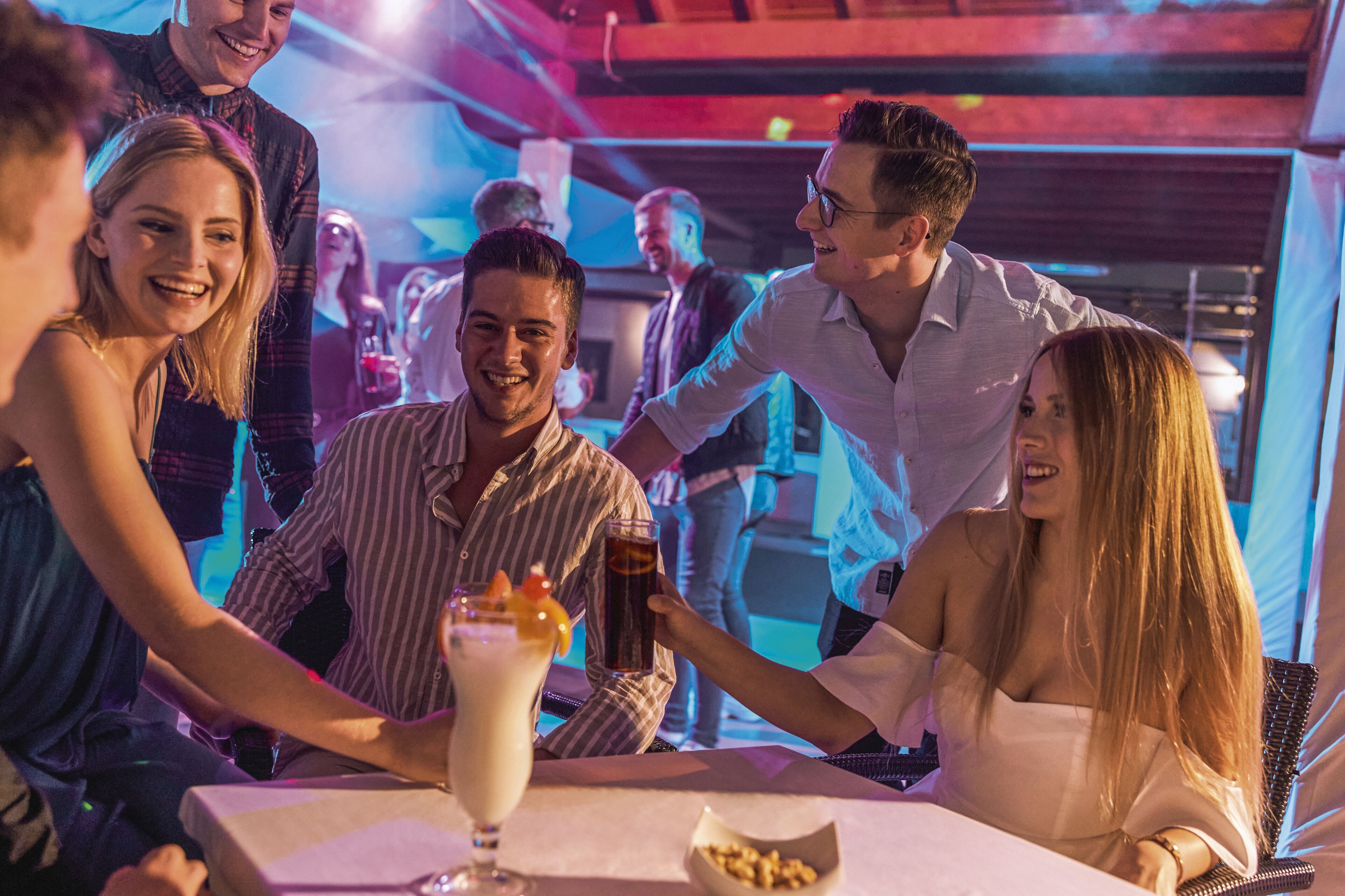 Un groupe de personnes est assis au bar, avec une boisson devant chacune d’elles.