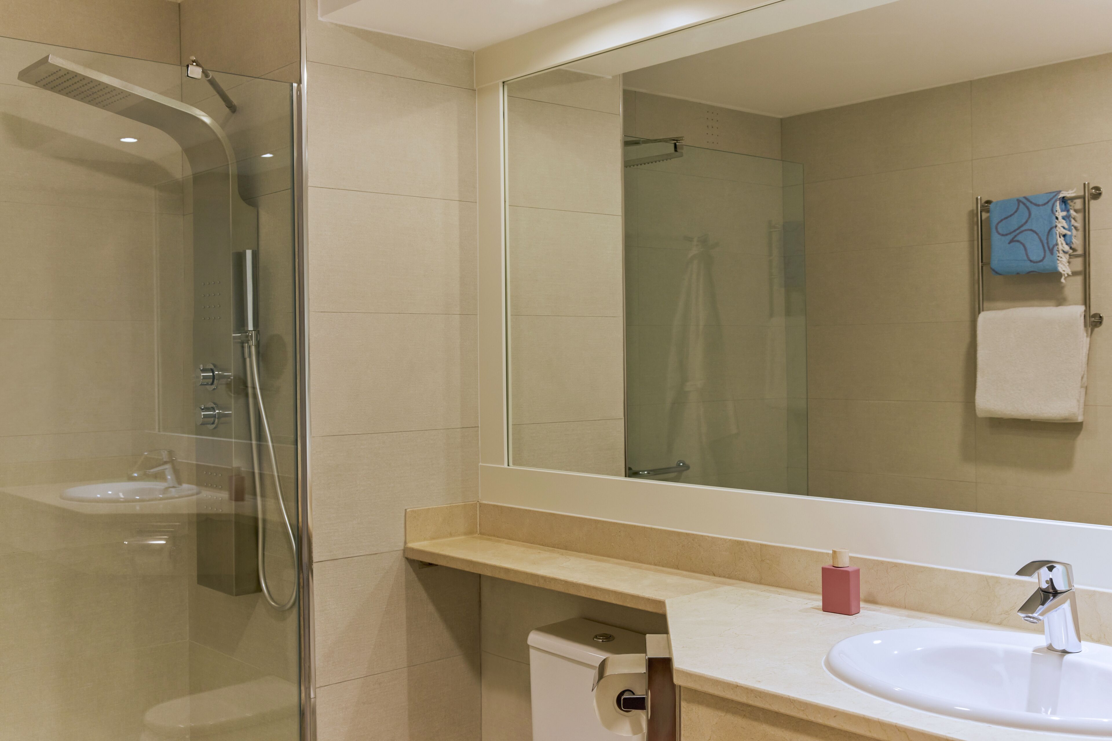 A modern bathroom with a glass-enclosed shower, a sink, and a large mirror.