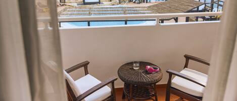 A balcony with wicker furniture, a small round table, and a view of the ocean.