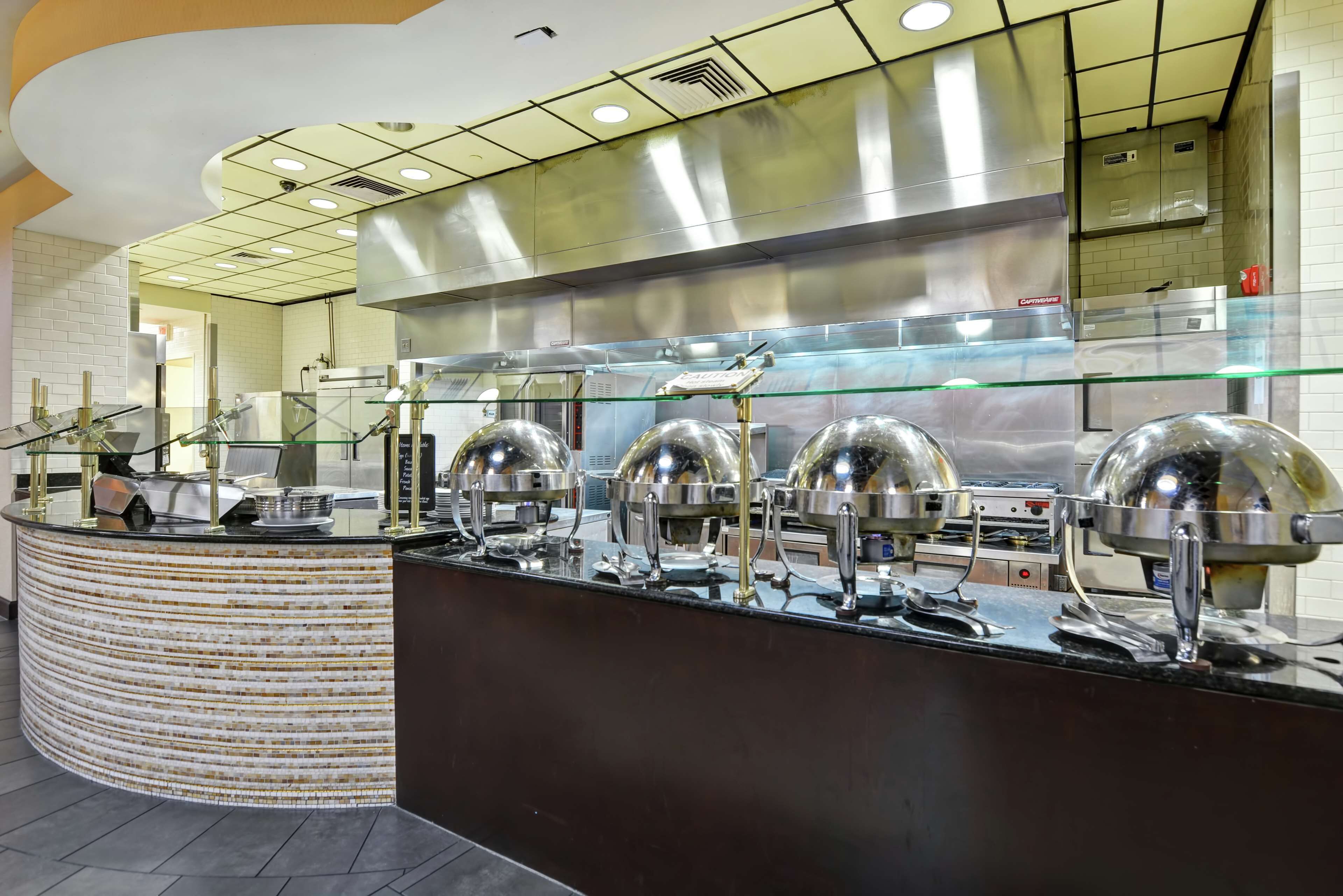 A commercial kitchen with stainless steel appliances, a glass display case, and a curved counter.