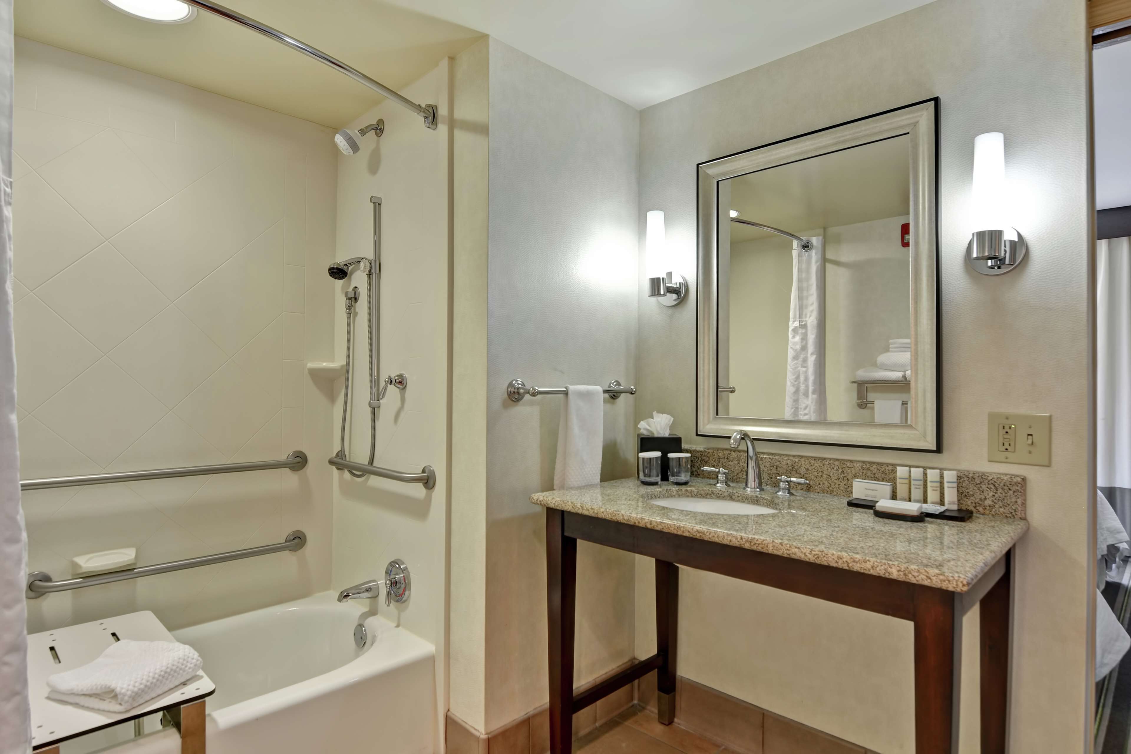 Een moderne badkamer met een bad, douche en wastafel met een grote spiegel.