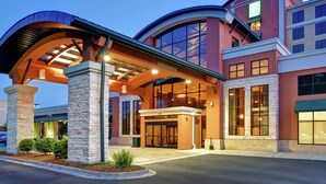 Ein moderner Hotel Eingang mit überdachter Zugangsbereiche, großen Fenstern und einem deutlichen Eingangsschild.