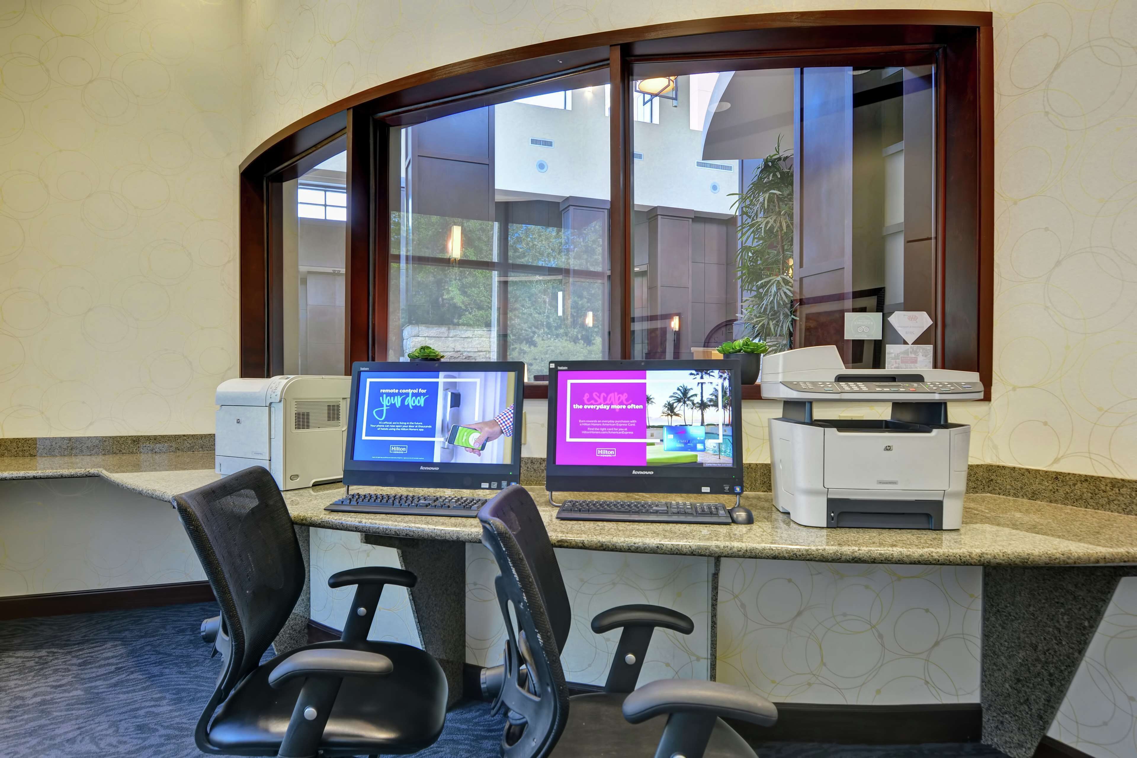 A hotel reception desk with two laptops, a printer, and two office chairs.