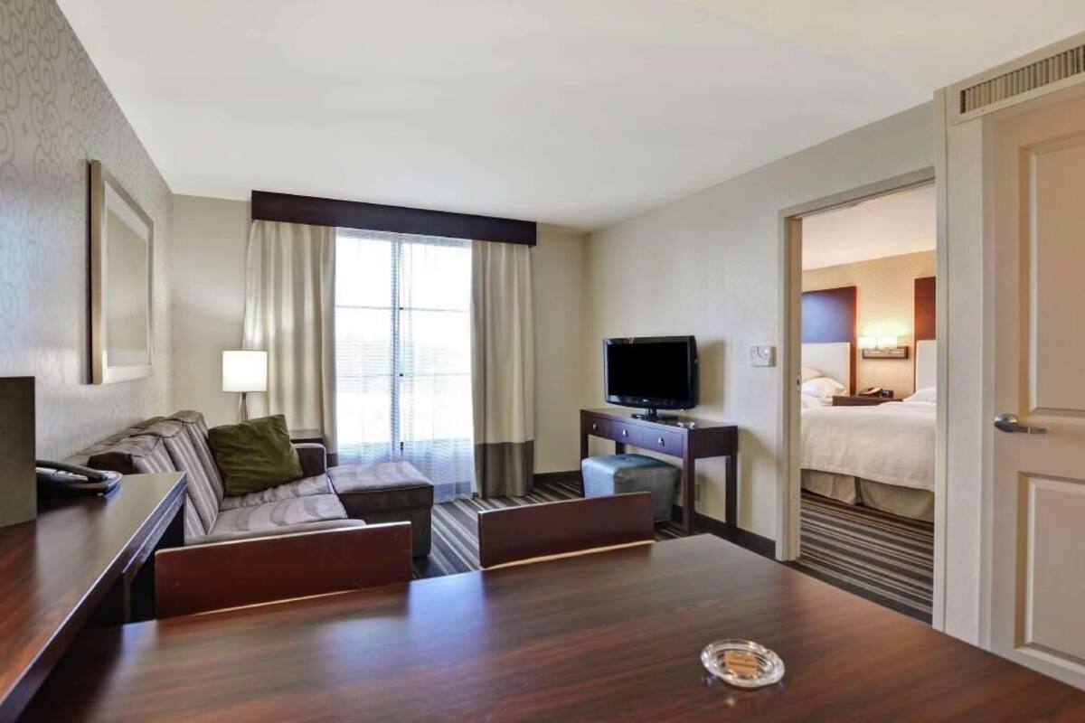 Habitación de hotel con sofá, televisión, mesa de comedor y cama.