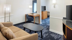 Une chambre d’hôtel avec un canapé, un bureau, une télévision et une lampe.