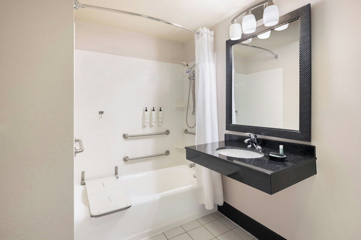 A modern bathroom with a bathtub, a vanity with a sink, a large mirror, and a shower area.