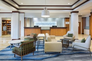 A lobby with a reception desk, seating area, and a view of the outside through a window. - Fairfield Inn & Suites Columbus Polaris (Columbus)