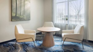 A room with a round table, two chairs, a large window, and a forest-themed painting on the wall. - Fairfield Inn & Suites Columbus Polaris (Columbus)