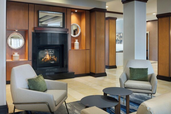 A modern lobby with a fireplace, two armchairs, a coffee table, and a large mirror. - Fairfield Inn & Suites Columbus Polaris (Columbus)