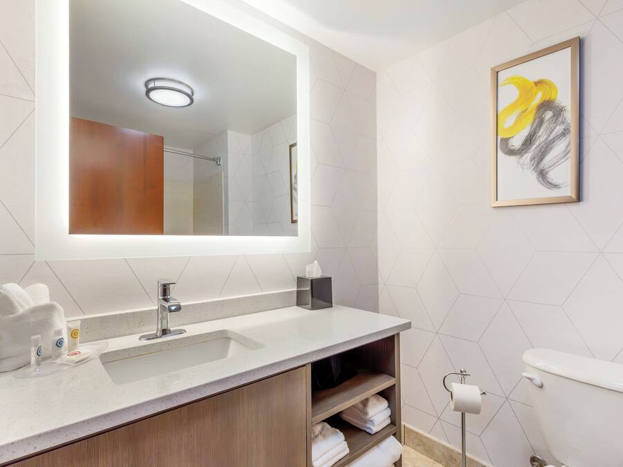 A modern bathroom with a large mirror, a sink, and a toilet.