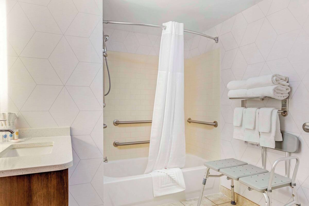 A modern bathroom with a shower, a bathtub, and a vanity with a sink.