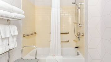 A bathroom with a bathtub, shower, grab bars, and a step stool.