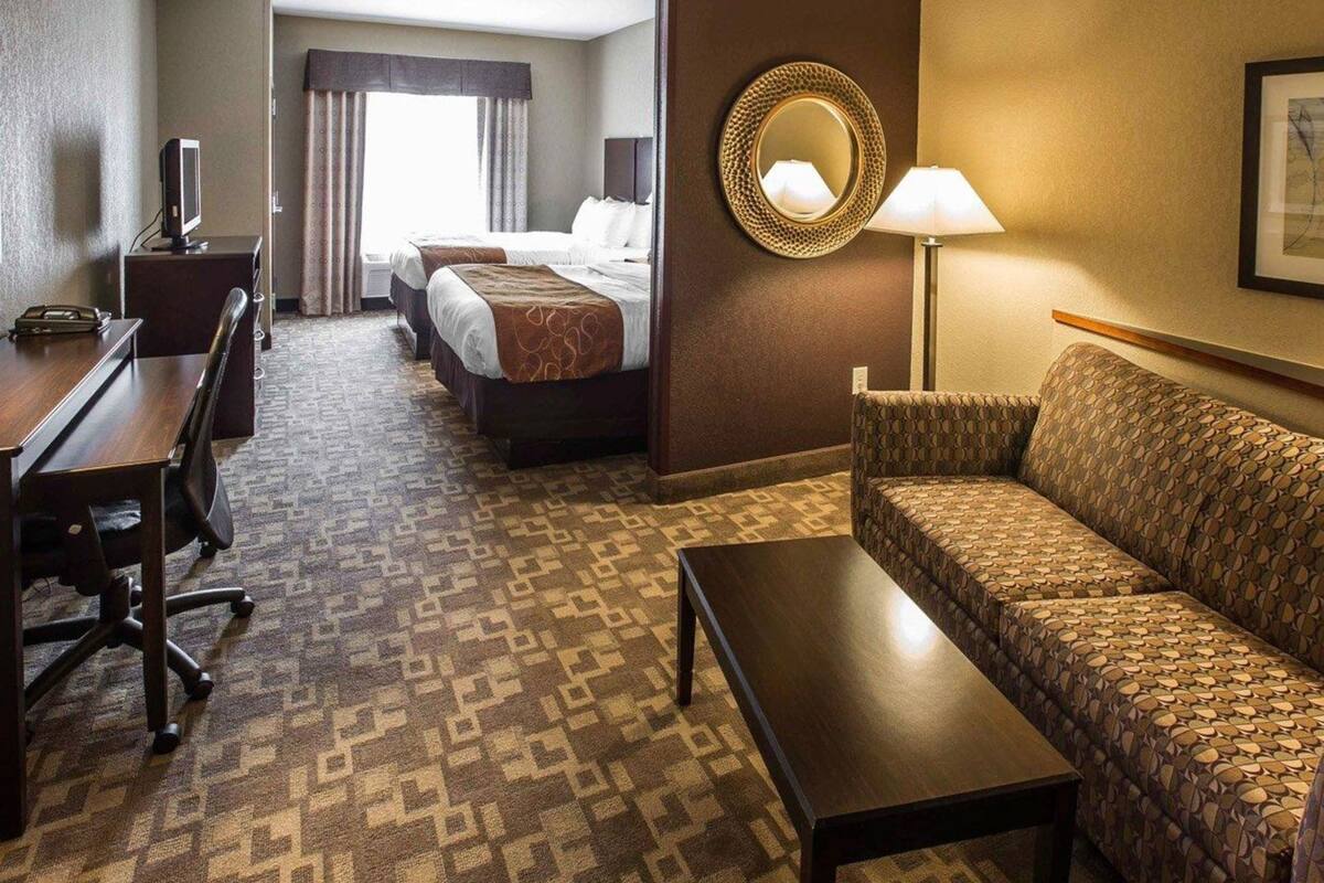 A hotel room with a bed, a desk, a sofa, a TV, and a lamp.