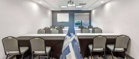 A conference room with a long table, chairs, a projector, and a whiteboard.