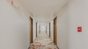 Un largo y estrecho pasillo de hotel con alfombra estampada y puertas de madera.