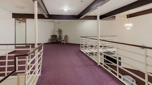 Una habitación con alfombra morada, paredes blancas y un traveño de madera en el techo.