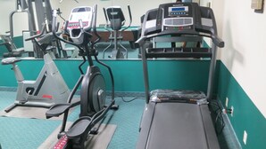 Une salle de sport équipée de divers appareils d’exercice, notamment des tapis de course, des vélos d’appartement et des appareils elliptiques.