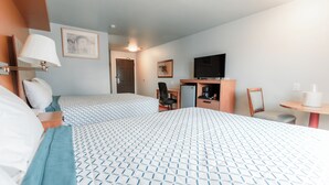 Une chambre d’hôtel avec deux lits, un bureau, une chaise, une télévision et une petite table.
