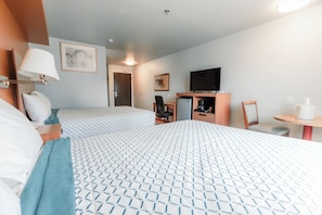 A hotel room with two beds, a desk, a chair, a television, and a small table. - Bay City Inn (Bellingham)