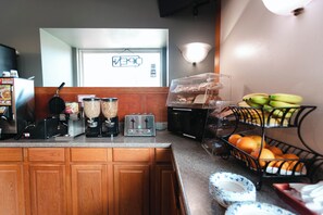 A kitchen with a toaster, coffee maker, and fruit baskets.