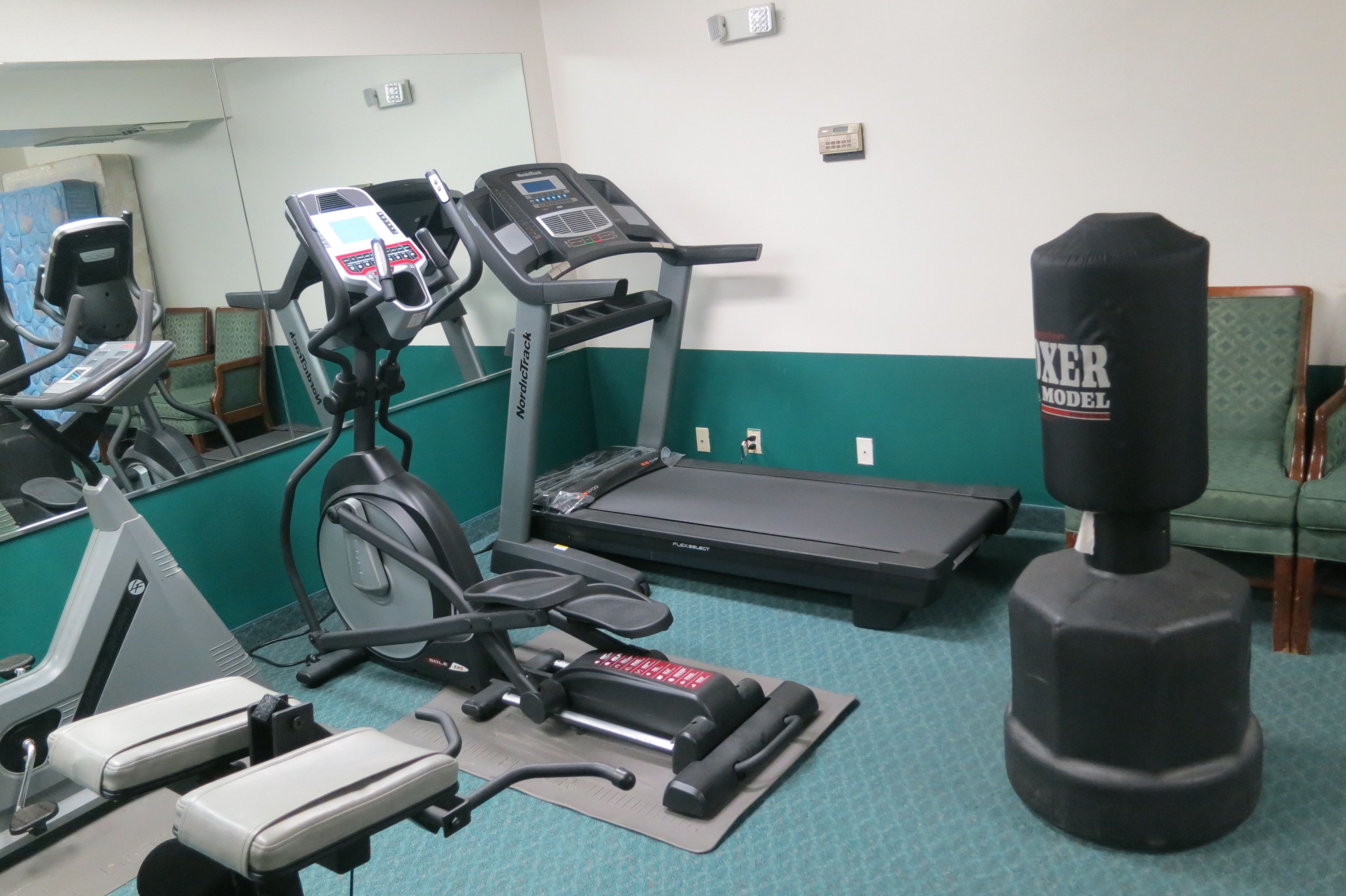 A gym with exercise equipment including a treadmill, stationary bike, and weight bench.