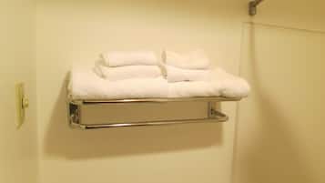A metal towel rack with folded white towels against a plain wall.