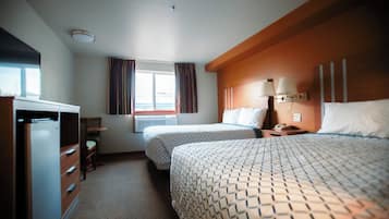 Une chambre d’hôtel avec deux lits, un bureau, une armoire et une fenêtre avec des rideaux.