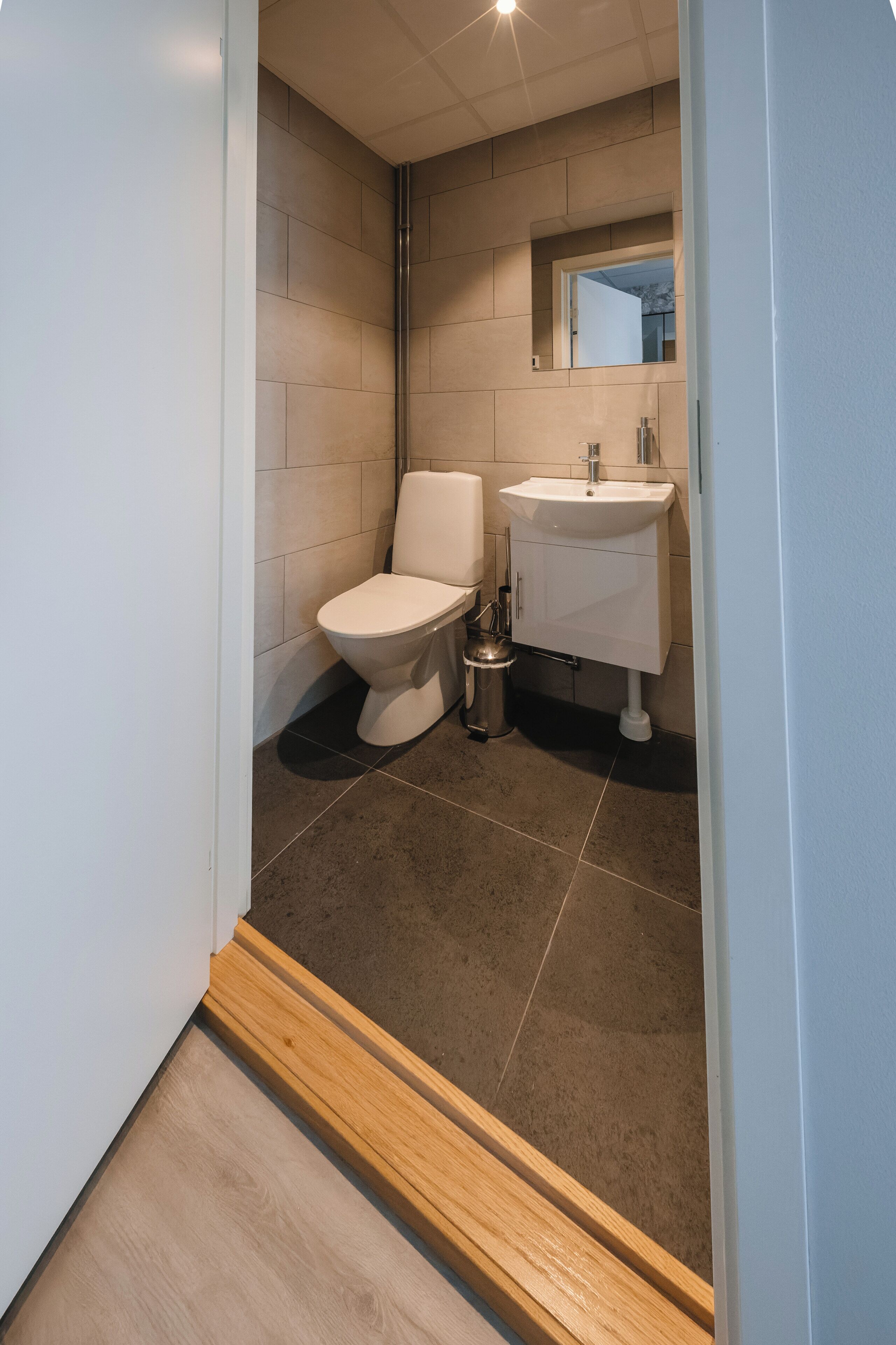 Un baño moderno con inodoro, lavamanos y espejo.