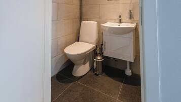 Un baño moderno con inodoro, lavamanos y espejo.