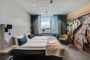 Une chambre d’hôtel avec un grand lit, une vue sur le paysage urbain par la fenêtre et une fresque représentant la ville sur le mur.