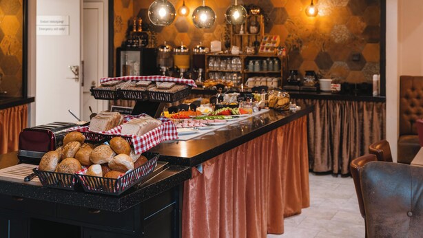 Un buffet garni de divers plats, une nappe à carreaux et des lampes suspendues décoratives.