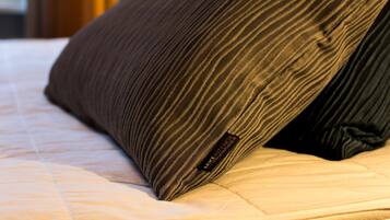 Primer plano de un almohadón a rayas sobre una cama, con una etiqueta de marca visible.