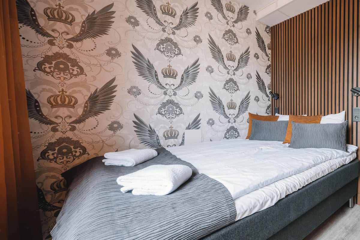 Un dormitorio moderno con cama, almohadas y un detalle decorativo en la pared.