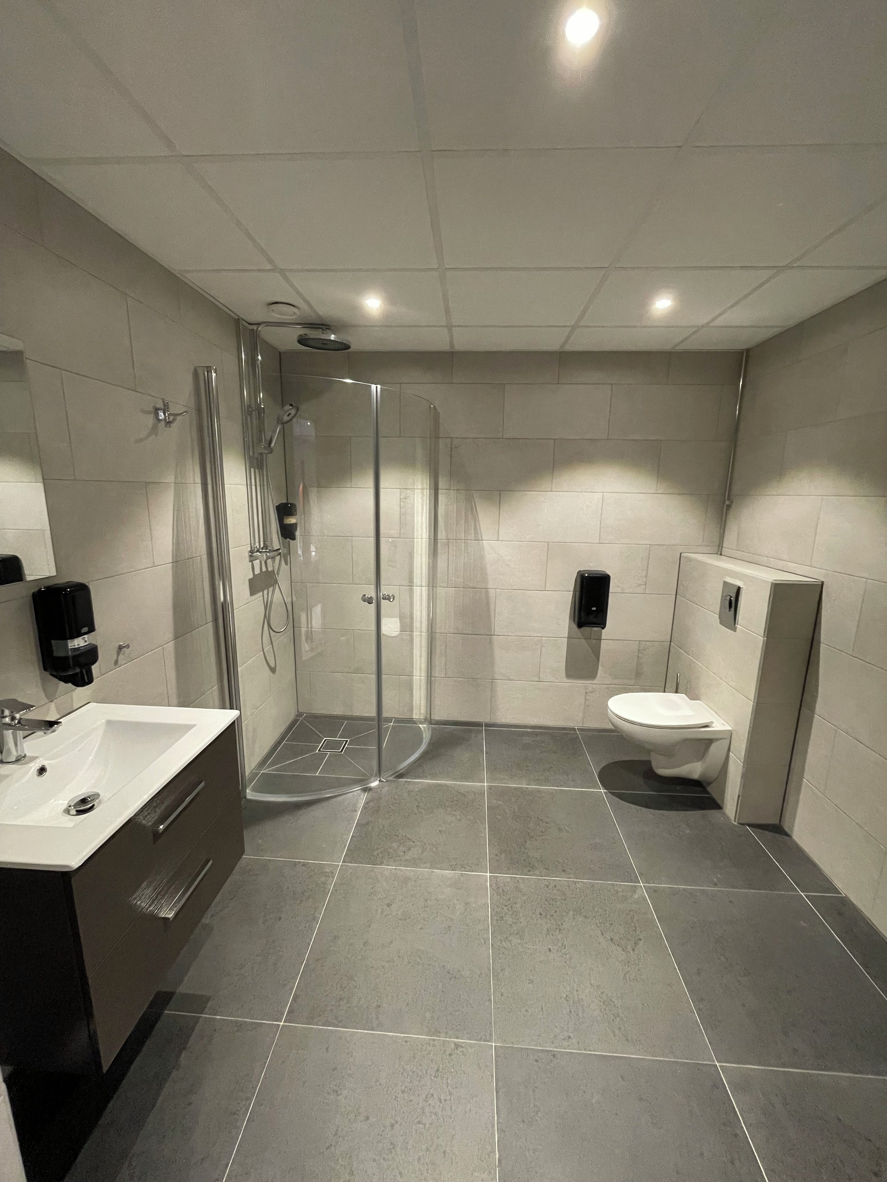 Un baño moderno con ducha envuelta en vidrio, inodoro y lavabo con espejo.