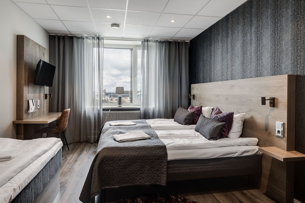 Habitación de hotel con una cama grande, un escritorio, una silla y un televisor.