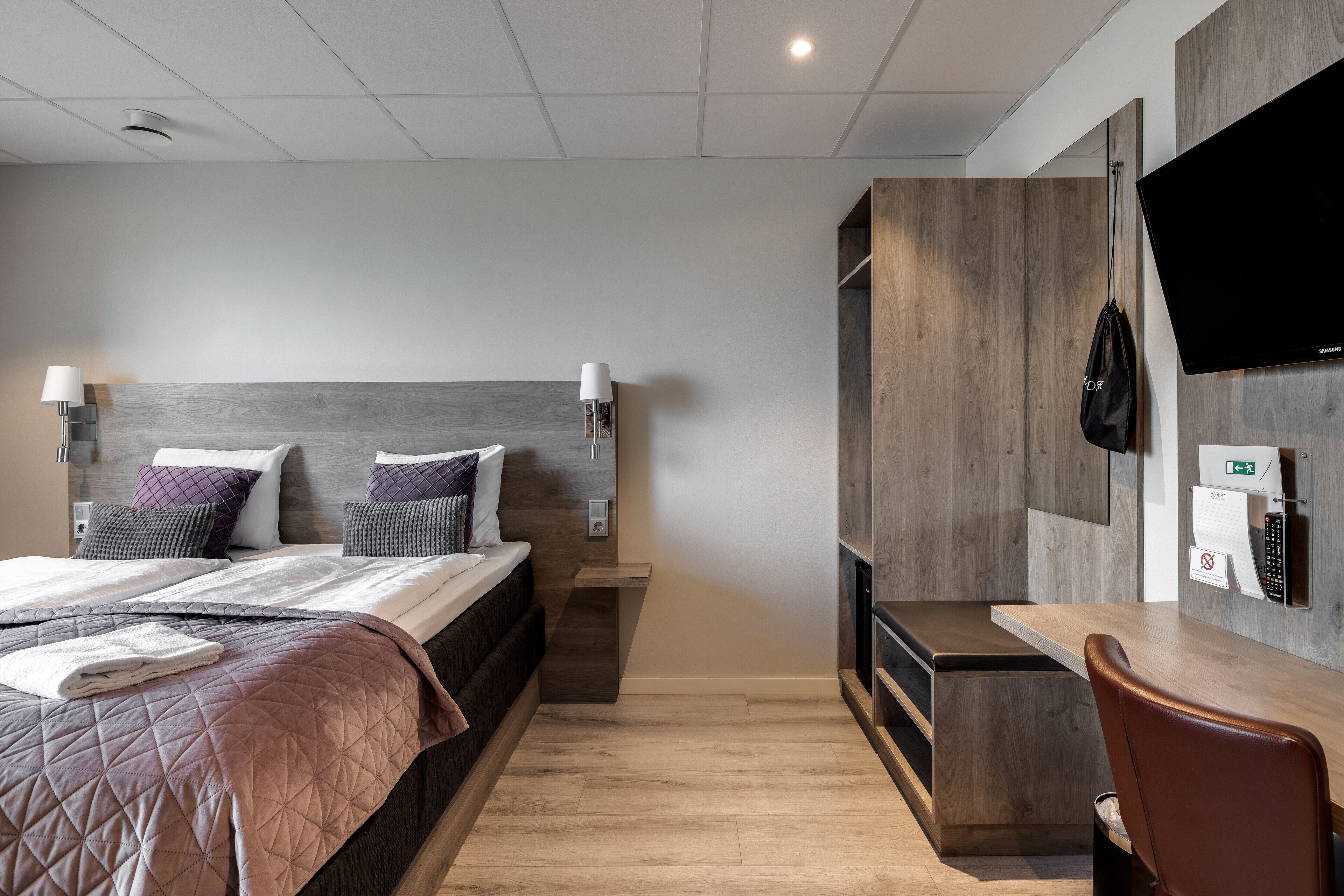 Une chambre d’hôtel moderne équipée d’un lit, de lampes de chevet, d’une télévision, d’un bureau et d’une chaise.