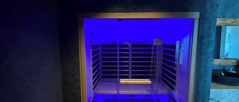 Una habitación con iluminación azulada, piso de madera y barandilla de metal.