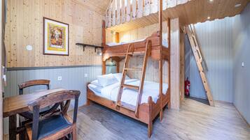 Cozy room with a wooden bunk bed, single chair, and framed picture on the wall.