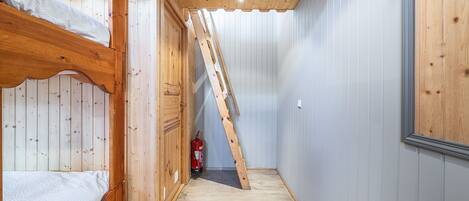 Habitación con literas de madera y escalera que lleva a un altiloque.