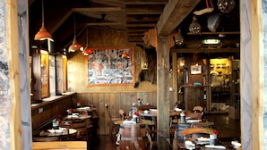 Un interior rústico de restaurante con mesas y bancos de madera, y una zona de bar central.