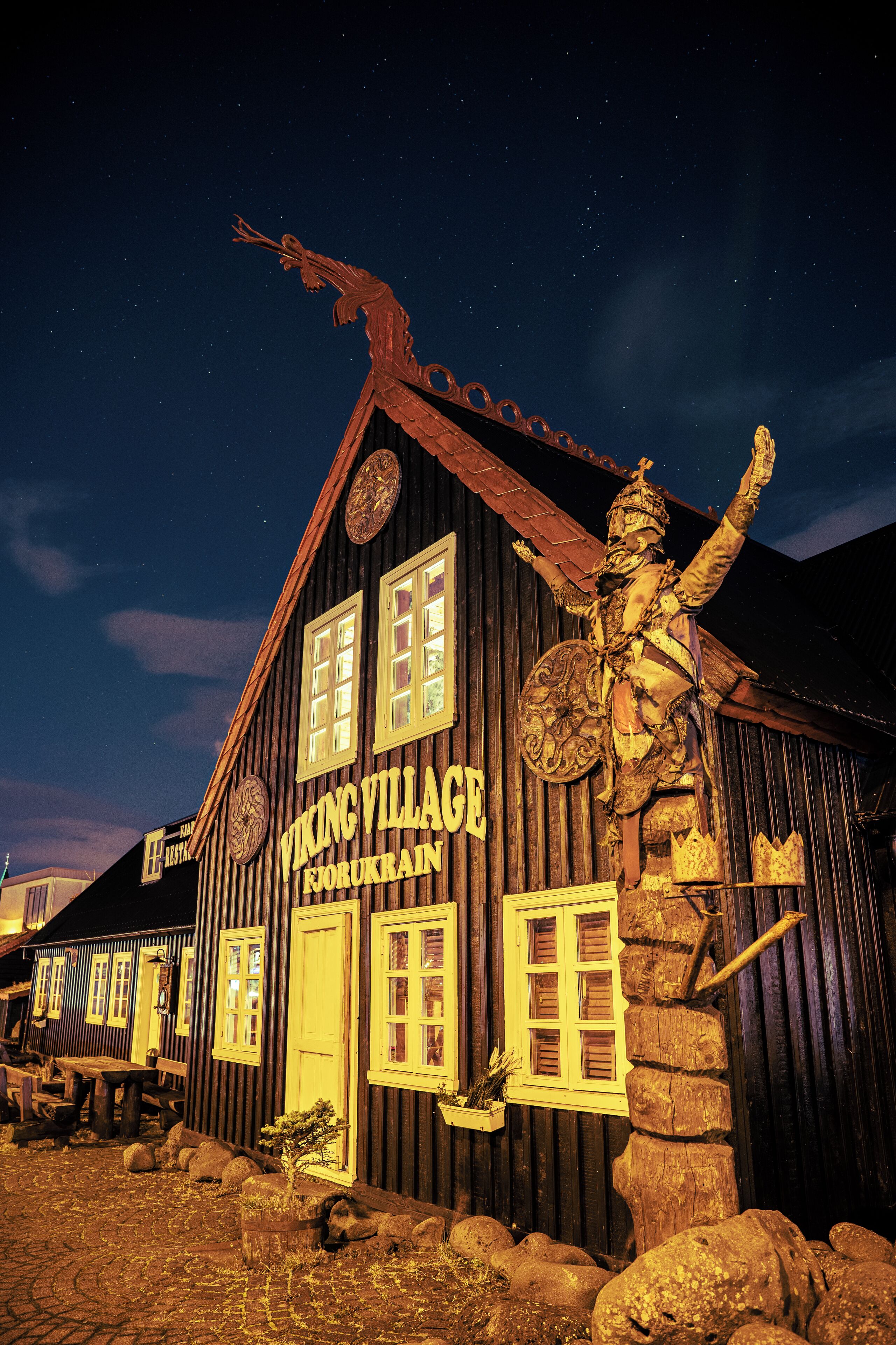 A Viking Village building with a wooden exterior, a large statue of a Viking warrior, and a sign with the building's name.