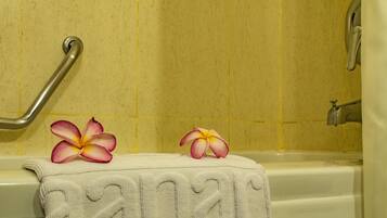 Un baño con una bañera, una toalla con diseño de corazón y dos flores sobre la toalla.