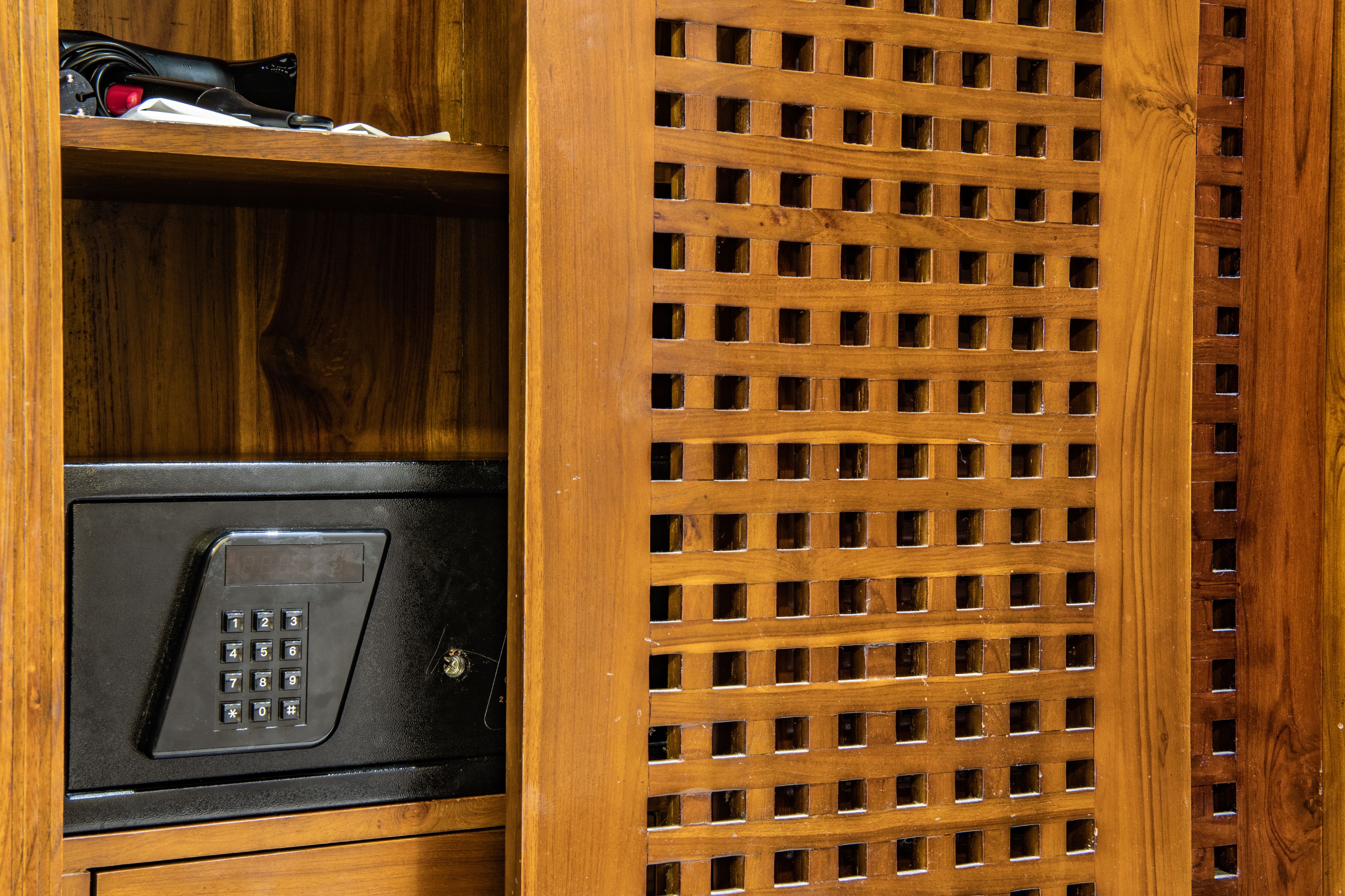 A wooden cabinet with a microwave and a shelf containing a black object and a red item.