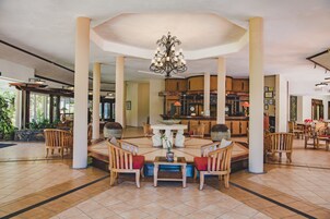Un vestíbulo amplio con una mesa redonda central, sillas de madera y un candelabro.