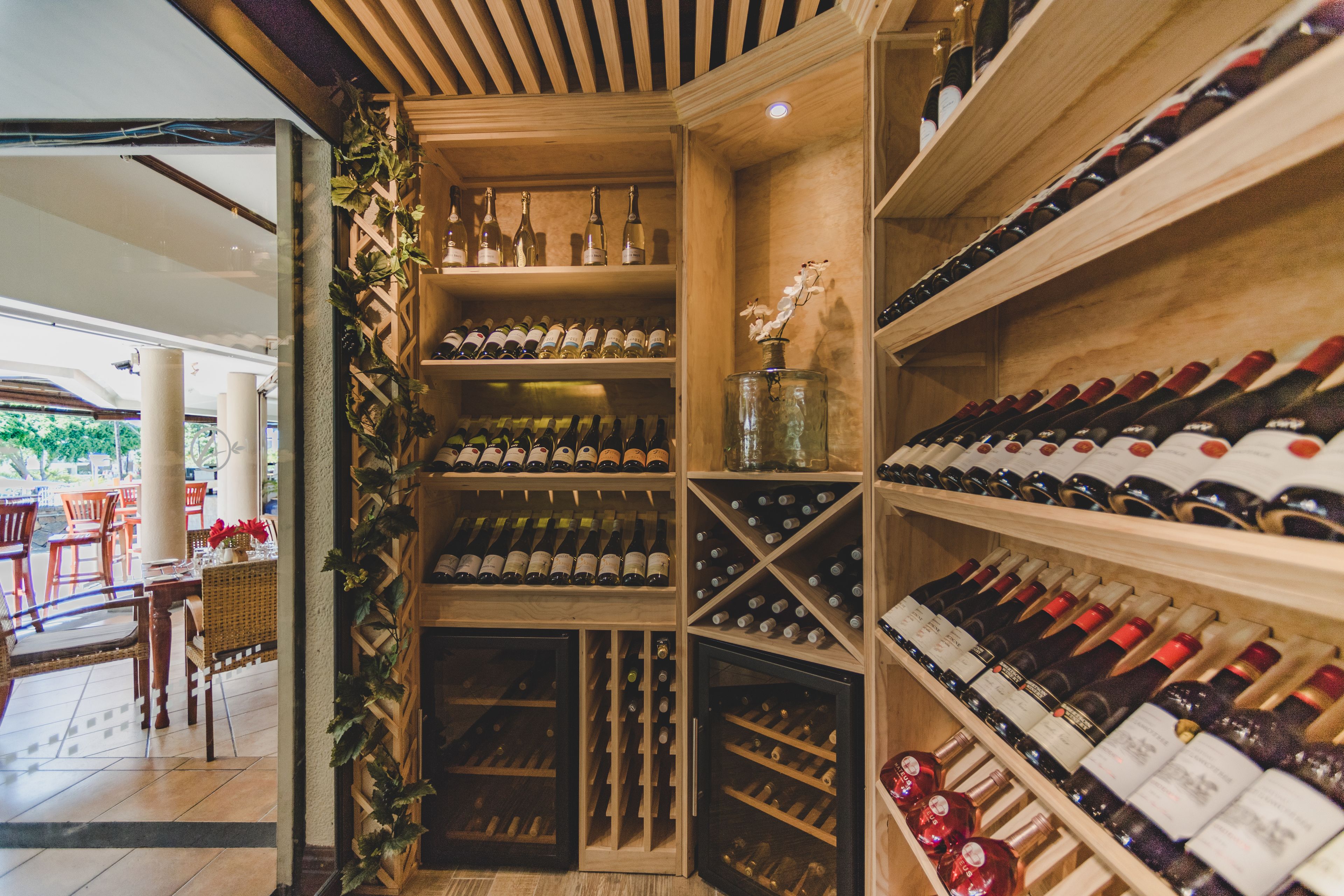 A wine cellar with wooden shelves and racks, and a glass display case with wine bottles.